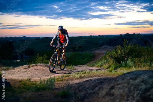 Cyclist Riding the Bike on Mountain Rocky Trail at Sunset