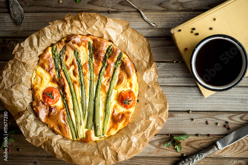 Pie with asparagus and tomatoes on wooden rustic table. Top view.