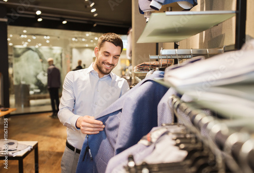 Fotografie happy young man choosing clothes in clothing store