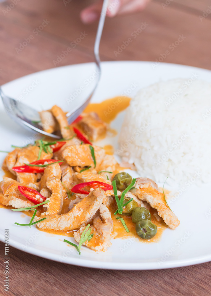 Red pork curry (Panang) with rice in white plate on wooden backg Red pork curry (Panang) with rice in white plate on wooden backg