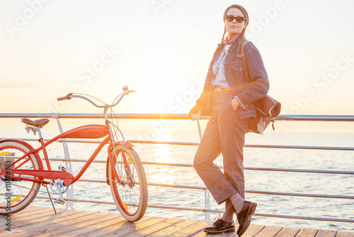 woman with vintage bicycle on seaside during sunset or sunrise