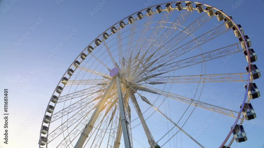 Majestic observation wheel rotating in amusement park, sunny blue sky background Majestic observation wheel rotating in amusement park, sunny blue sky background