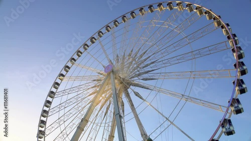 Majestic observation wheel rotating in amusement park, sunny blue sky background photo