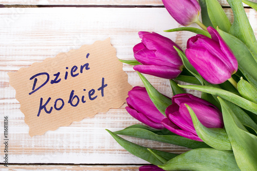 Women's Day card and a bouquet of beautiful tulips on wooden background, with Polish words "Women's Day"