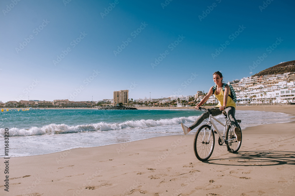 Fototapeta premium carefree woman with bicycle riding on beach sand having fun and