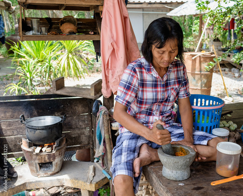 Senior women cooking outdoor, Thai countryside and local lifestyle, mother cooking outdoor sitting in hut with pot and firing firewood in stover