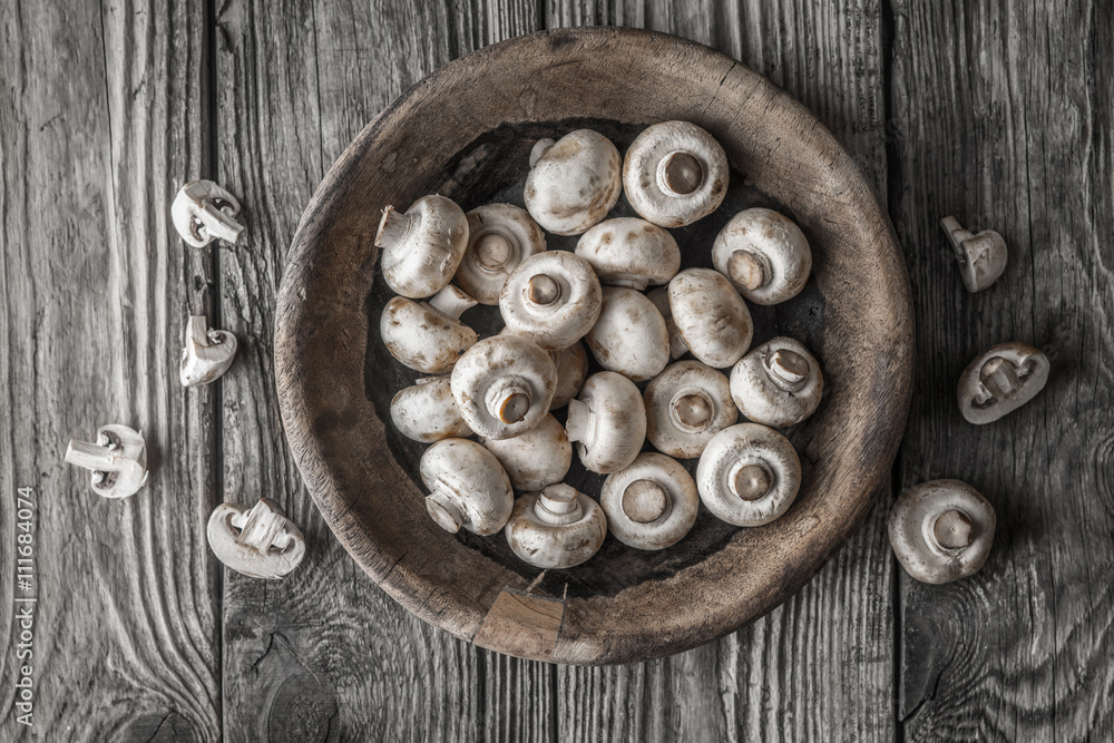 Champignon on the wooden bowl on the old table top view Champignon on the wooden bowl on the old table top view