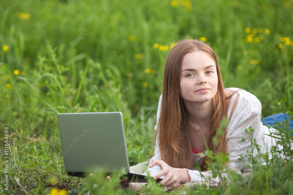 Young smiling woman with notebook in park looking at notebook computer. Young smiling woman with notebook in park looking at notebook computer.
