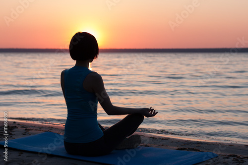Girl meditating on beach at sunset © milogrodskiy
