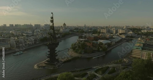 Aerial view of Peter the Great Statue on a summer spring day at sunset. Crowds of people walking along the park near river.  