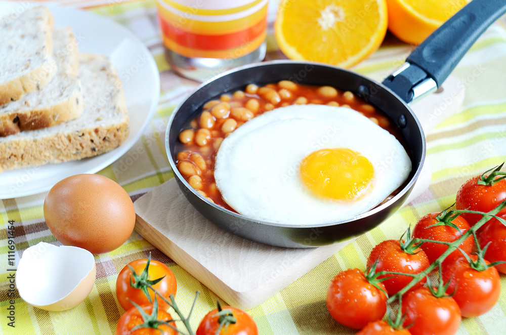 Fried egg with beans, toast bread, fresh juice, tomatoes and oranges Fried egg with beans, toast bread, fresh juice, tomatoes and oranges