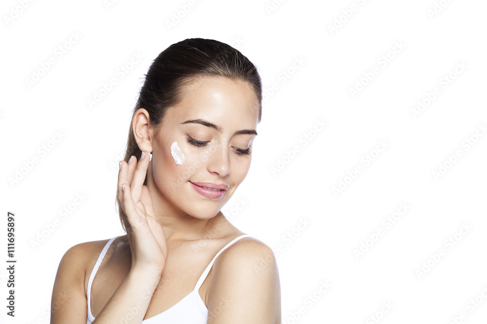 Portrait of young woman applying moisturizer cream on her pretty face. Isolated on white background Portrait of young woman applying moisturizer cream on her pretty face. Isolated on white background