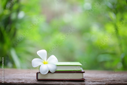 Notebook with plumaria flower on wooden table