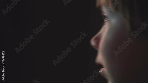 Young boy watching cartoons in a dark room on a computer
