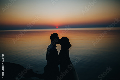 man and woman sitting at sunset on a wooden quay on a lake in the woods