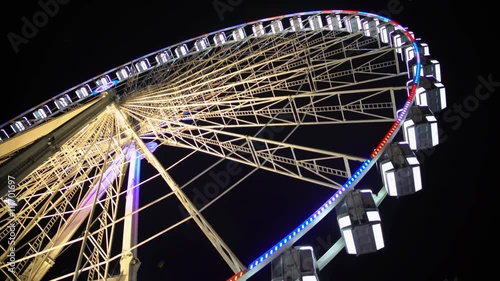 Huge observation wheel stops moving at night amusement park, entertainment