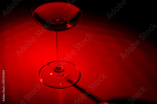Red wineglass on a red dark background