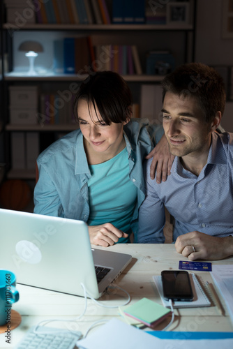 Happy young couple surfing the web at home