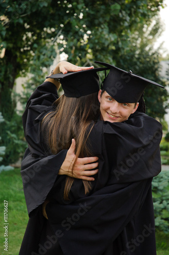 Happy graduate hugging his classmate.