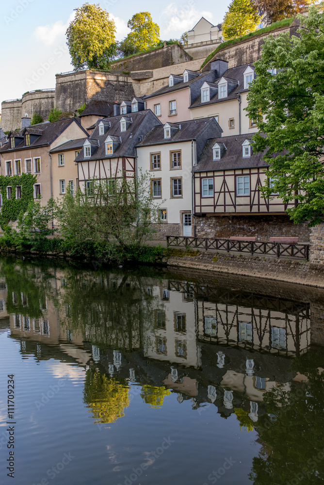 Colorful buildings reflecting in the Alzette river in the city o