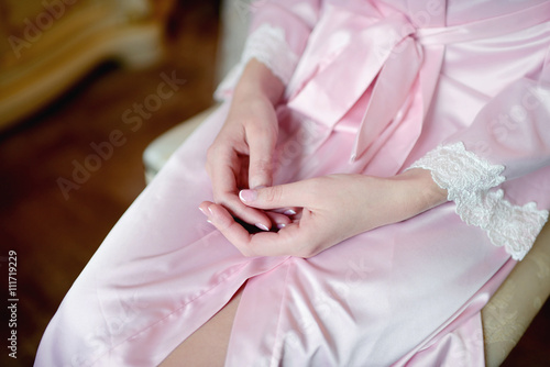 Hands of beautiful bride in white dressing gown. Beauty model girl in wedding robe. Female portrait with manicure. Close-up woman's arms. Cute lady indoors