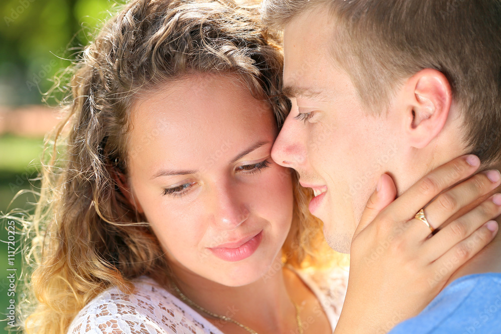 Fototapeta premium Close-up side view of a loving couple embracing in the park