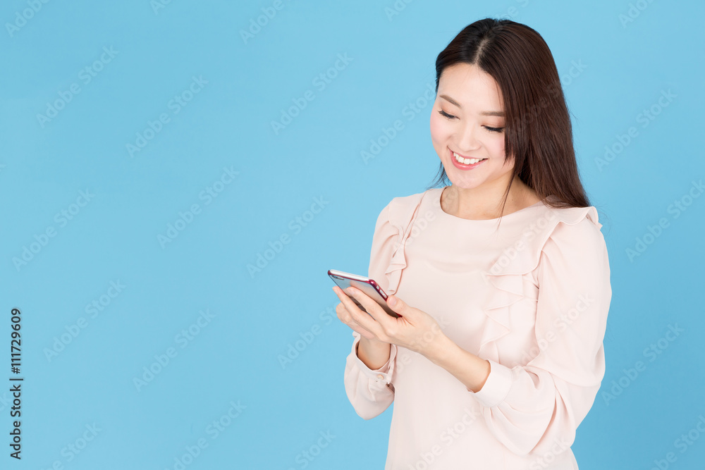 portrait of asian woman using smart phone isolated on blue background portrait of asian woman using smart phone isolated on blue background