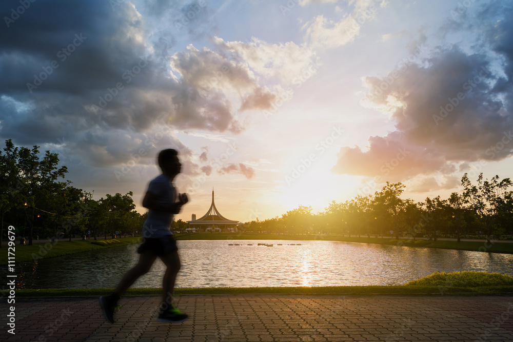 Fototapeta premium Silhouette of man jogging In the park in twilight. Motion blur.