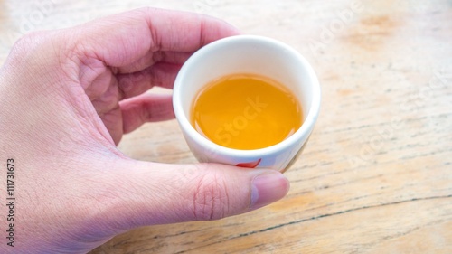 hand holding a cup of tea with wood table background