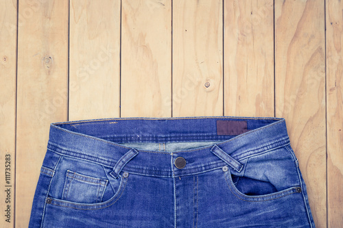 Blue jeans on wooden background top view