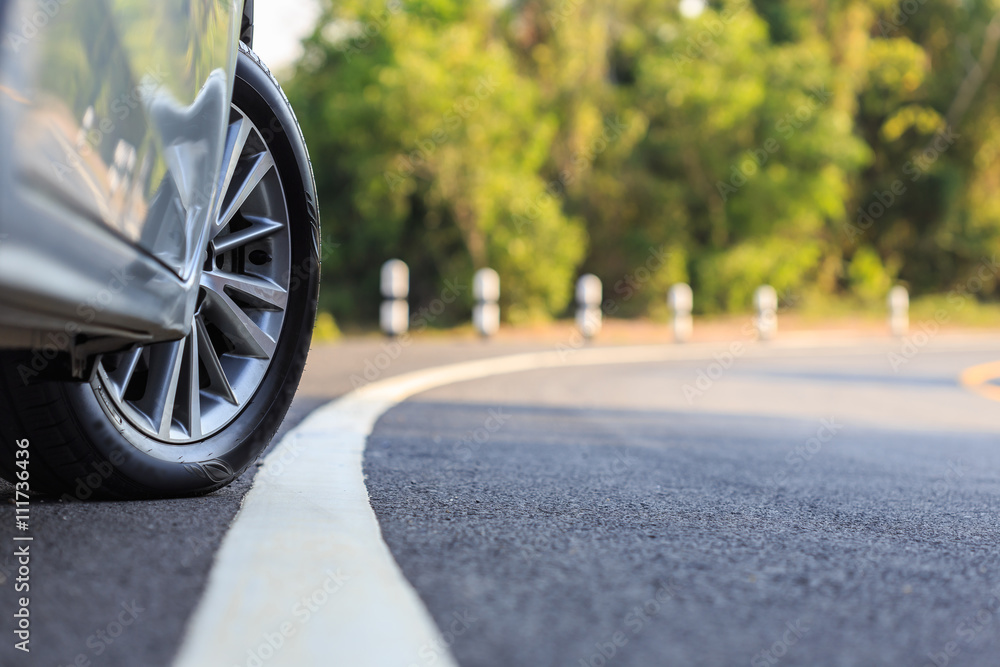 Naklejka premium Front car wheel on the asphalt road