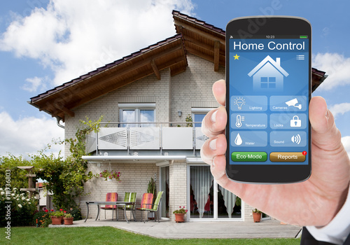 Person Hand Holding Mobile Phone With Home Control System