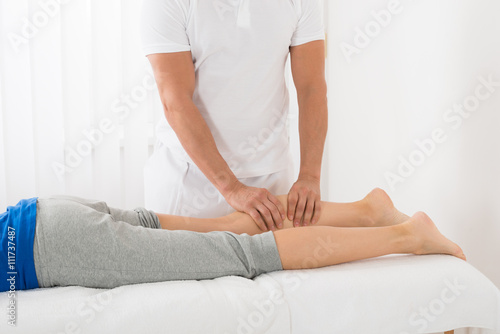 Man Giving Leg Massage To Woman