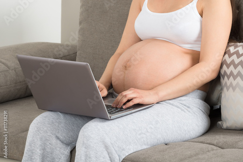 Expecting Woman Using Laptop At Home
