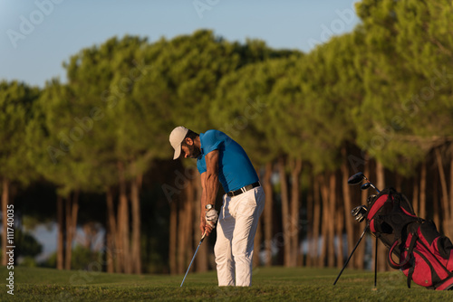 golfer hitting a sand bunker shot on sunset