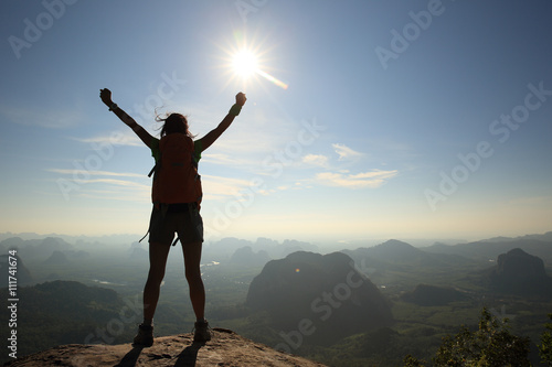 cheering woman hiker at sunrise mountain peak
