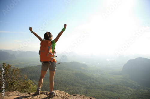 cheering woman hiker at sunrise mountain peak