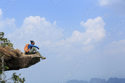 successful woman hiker enjoy the view at mountain peak cliff