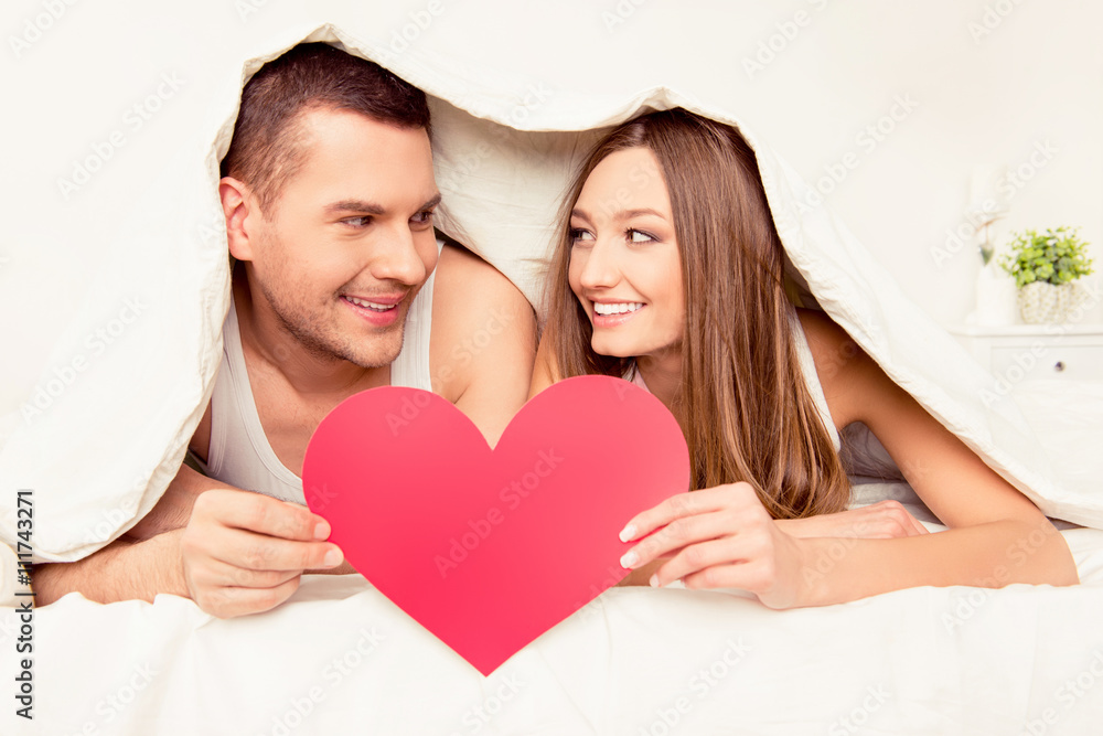 Portrait of happy man and woman covering with blanket and holdin Portrait of happy man and woman covering with blanket and holdin