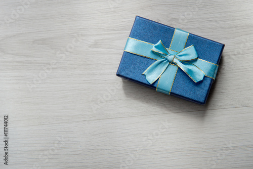 Blue gift box on gray wooden texture background with copyspace f