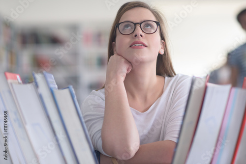 portrait of famale student selecting book to read in library