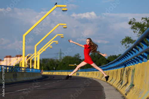 Beautiful ballerina jumping on a bridge with graffiti