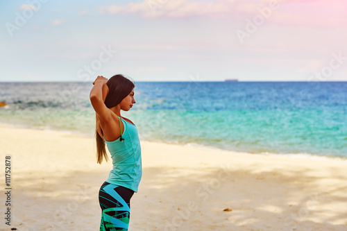 Young woman stretching on the beach , sport activities