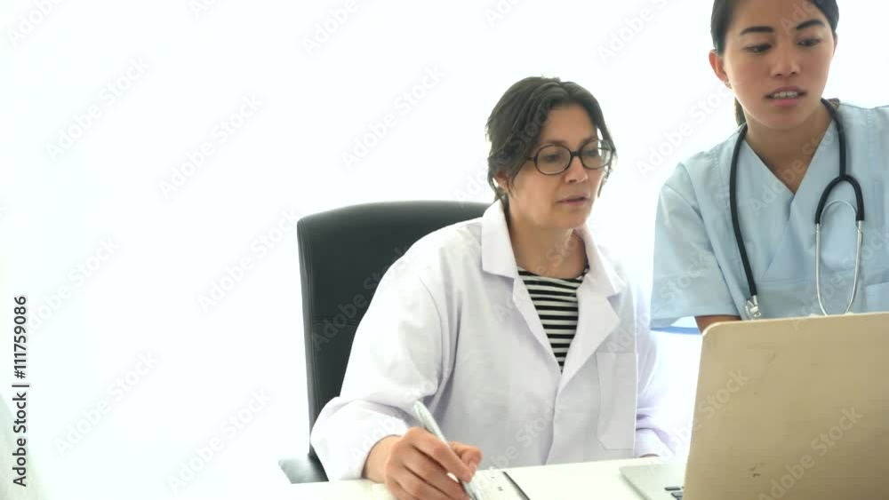 Asian medical assistant showing her tutoring doctor some results on computer desktop Asian medical assistant showing her tutoring doctor some results on computer desktop