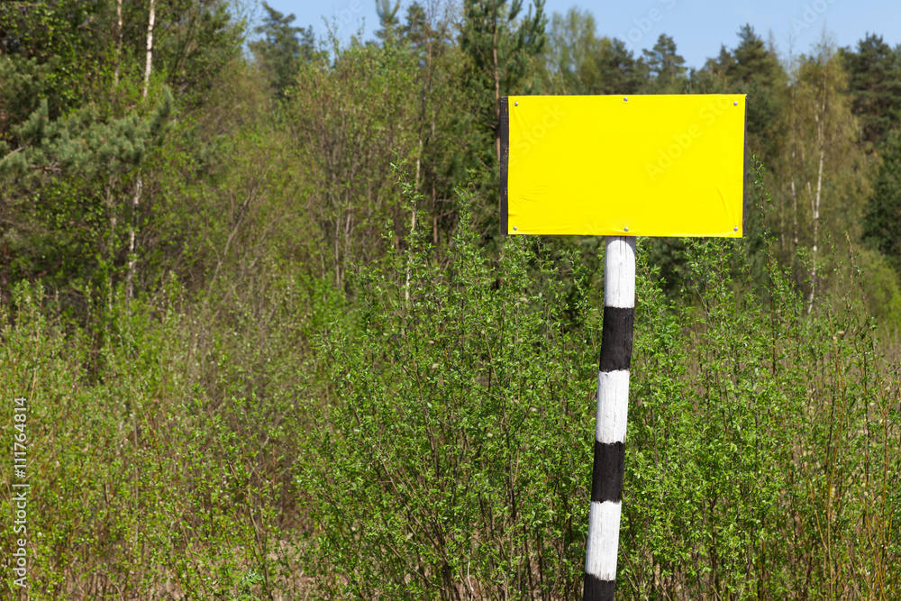 Empty yellow sign board on striped post Empty yellow sign board on striped post