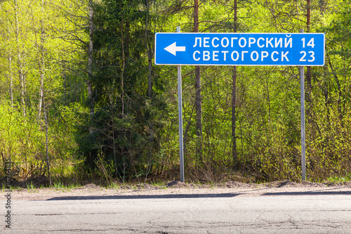 Blue road sign near highway in summer