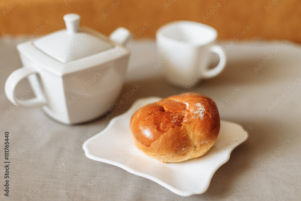 bun and tea breakfast on a gray fabric background white dishes bun and tea breakfast on a gray fabric background white dishes