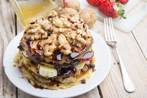 Pancakes with banana , walnut & chocolate on wood background
