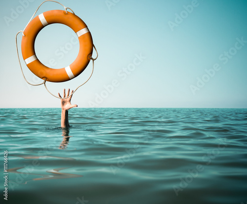Drown man with rised hand getting lifebuoy help in sea photo