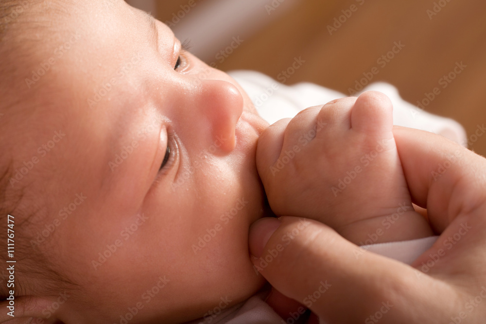 Gentle moment Baby kid sucking mothers finger closeup portrait with little field of sharpness on the babies nose and fingers Gentle moment Baby kid sucking mothers finger closeup portrait with little field of sharpness on the babies nose and fingers